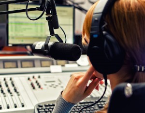 Rear view of female dj working in front of a microphone on the radio